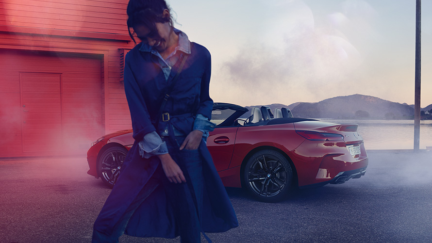 BMW Z4 M40i Roadster G29 mit geöffnetem Verdeck BMW Z4 M40i Roadster G29 Dreiviertel Heckansicht mit geöffnetem Verdeck und Frau im Vordergrund