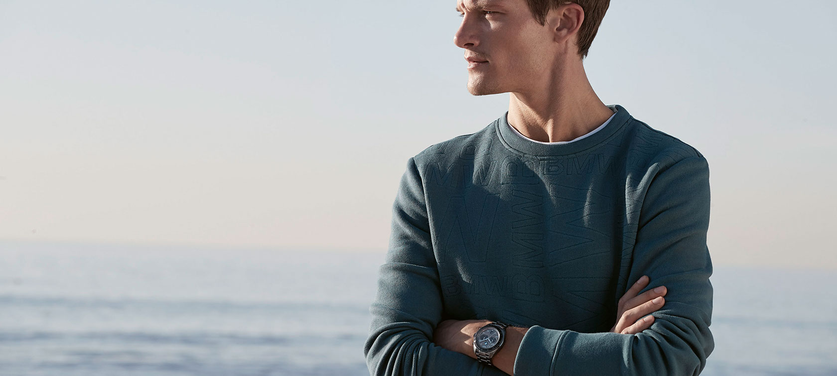 BMW Sweatshirt Herren. Ein junger Mann trägt das BMW Sweatshirt Herren.