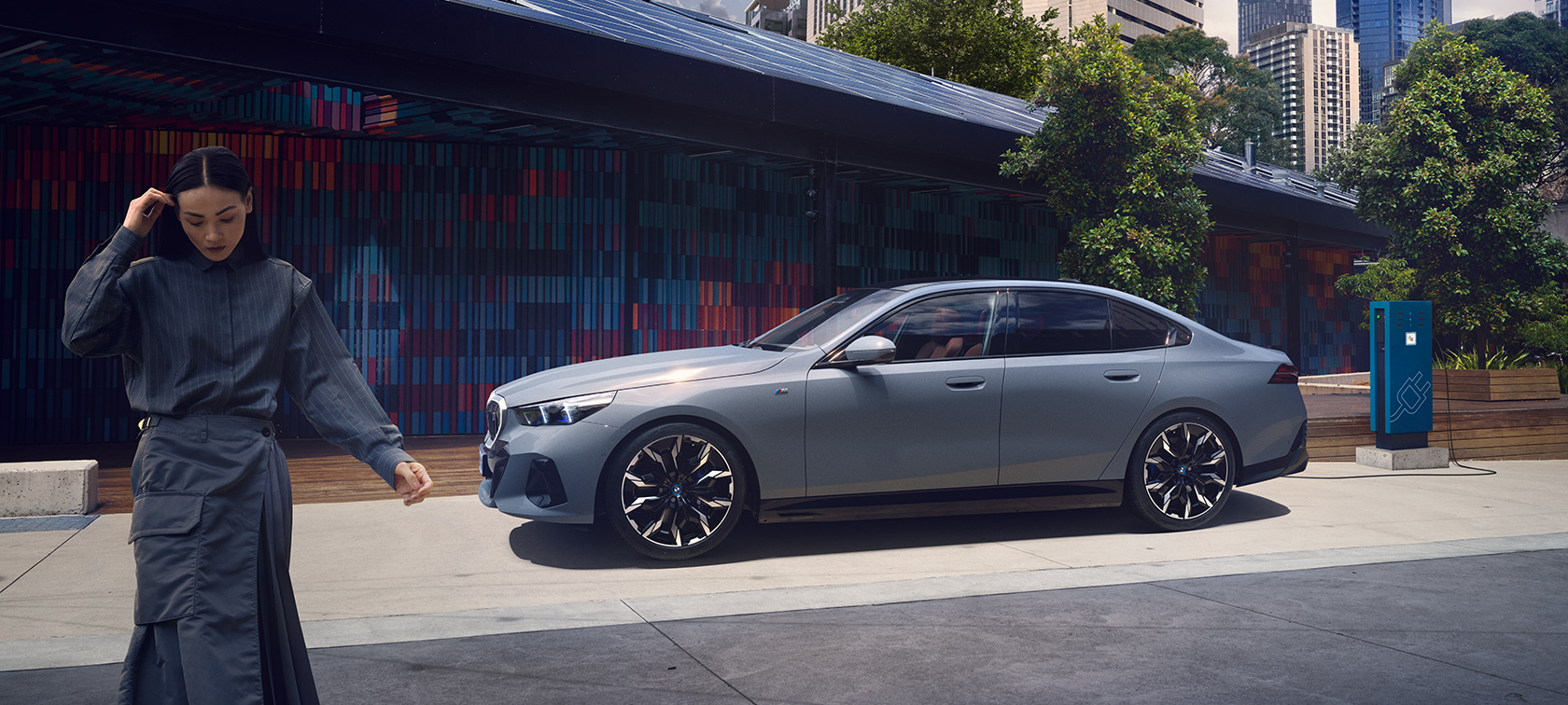 BMW i5 G60 Seitenansicht Ladesituation BMW i5 G60 Seitenansicht mit Frau Ladesituation