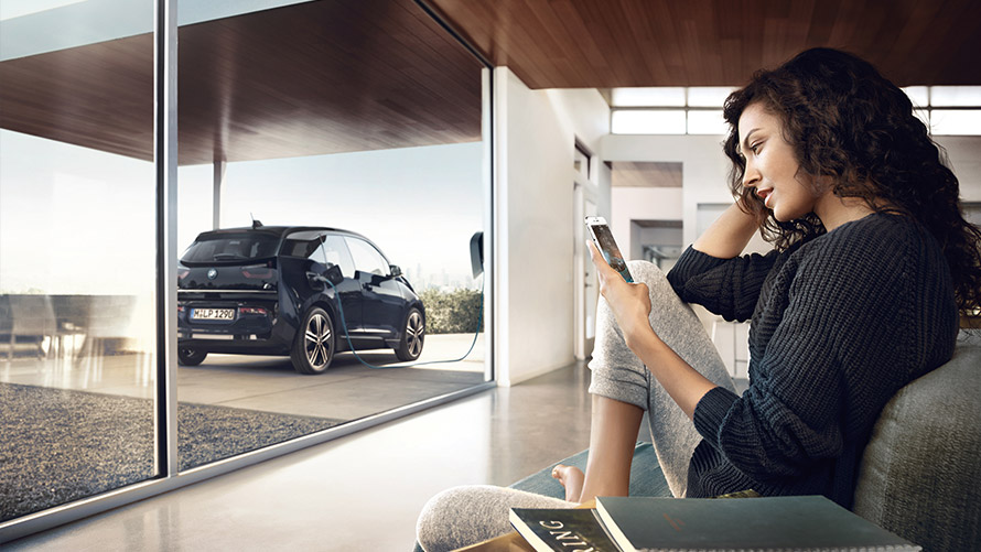 Digital Charging Service Frau nutzt zu Hause Funktion „Digital Charging Service“ über Smartphone für ihren BMW i3