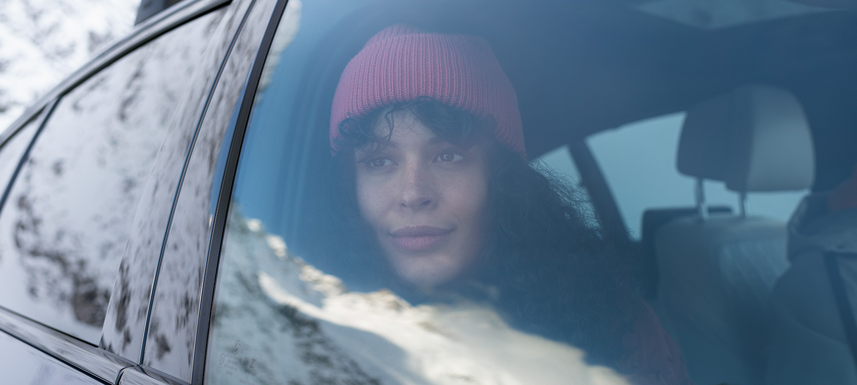 Frau schaut aus dem Autofenster eines BMW BMW Herbst- und Winterzubehör Frau schaut aus dem Autofenster eines BMW