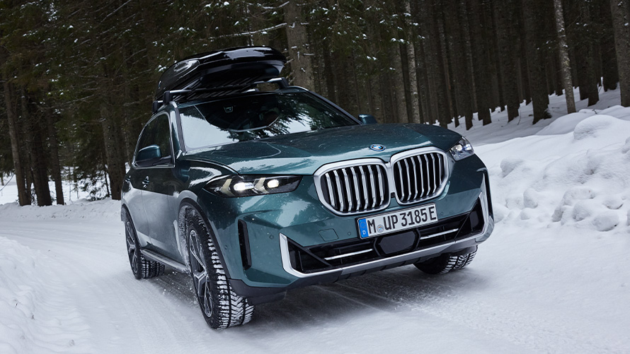 BMW Winterkompletträder an BMW X5 (G05 LCI) auf verschneiter Straße im Wald BMW Winterkompletträder an BMW X5 (G05 LCI) auf verschneiter Straße im Wald