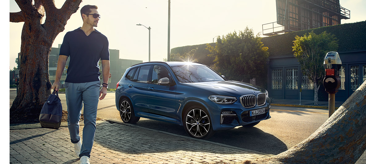 Mann mit Sonnenbrille vor blauem BMW Mann mit Sonnenbrille vor blauem BMW