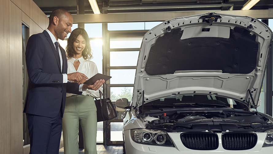 Fahrzeugchecks und Wartung BMW Service Kundin und BMW Service Mitarbeiter besprechen Check und Wartung am BMW