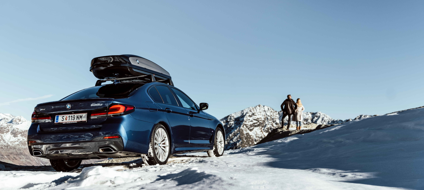 Original BMW Zubehör und BMW Service für Herbst und Winter Frau und Mann sehen in die Ferne auf einem Berg