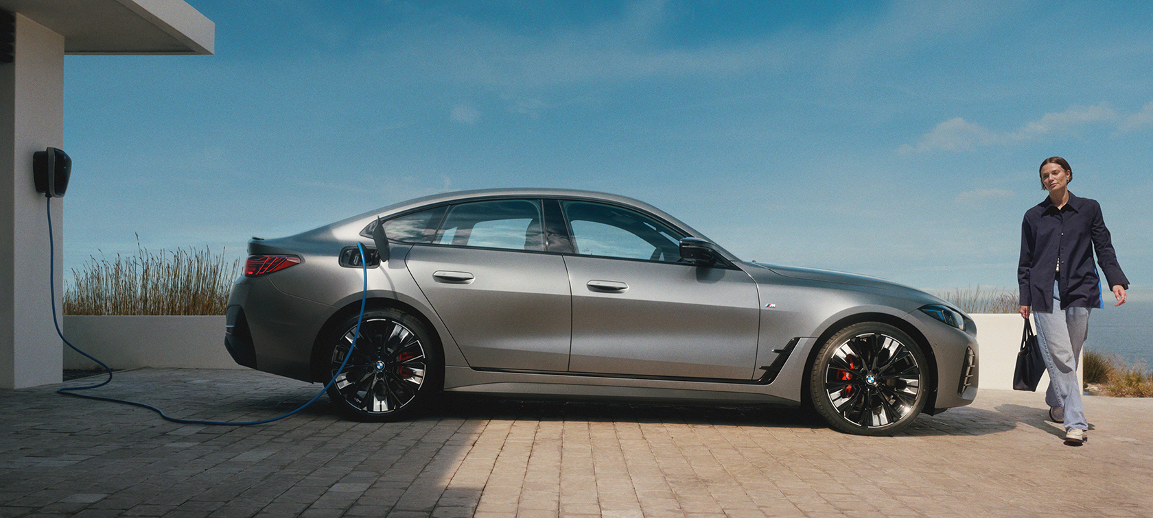 Eine Frau geht um einen vollelektrischen BMW: Eine Frau geht um einen vollelektrischen BMW: