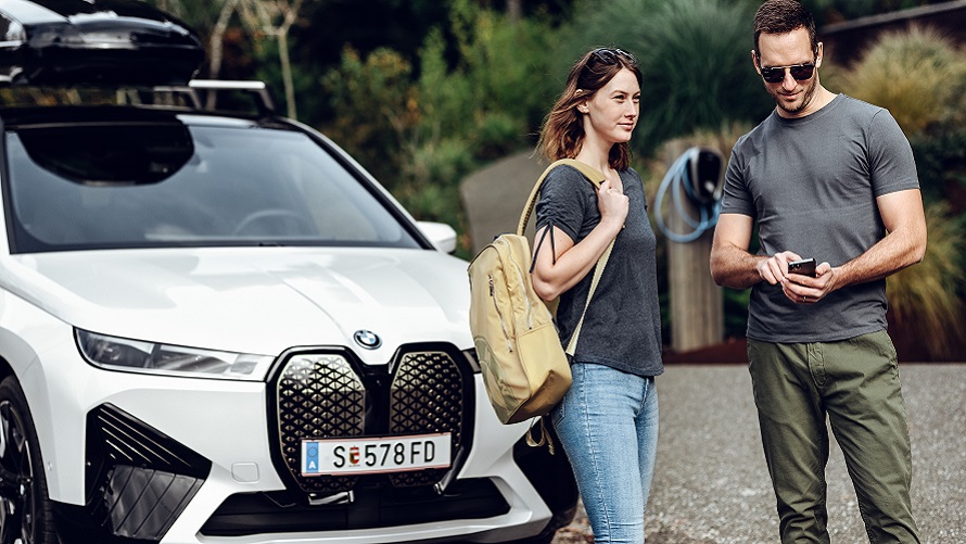 Frau sitzt auf einem Steg und guckt auf ihr Smartphone BMW Frühlings- und Sommerzubehör Frau sitzt auf einem Steg und guckt auf ihr Smartphone