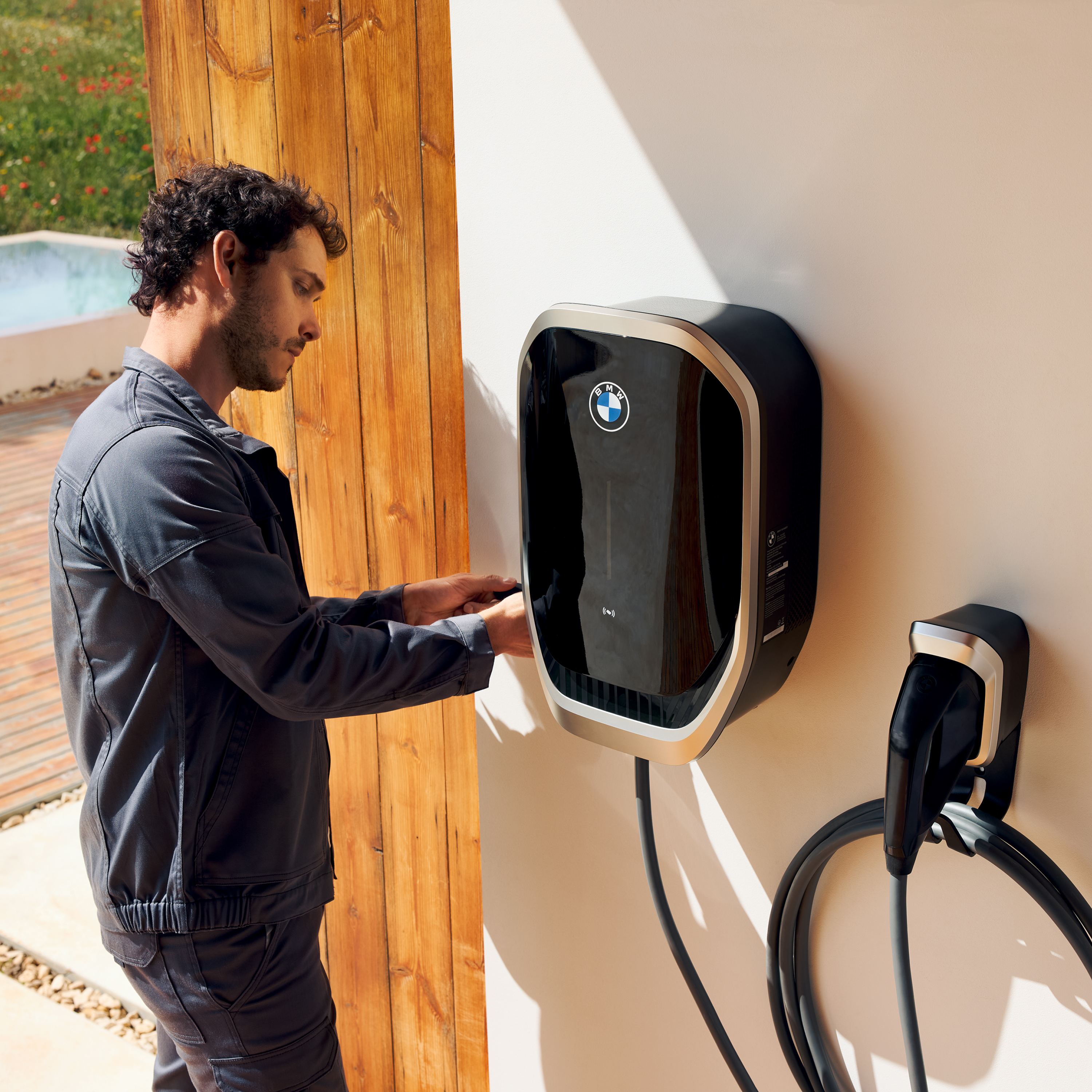 Eine Person schließt ein Ladekabel an einer BMW Wallbox an