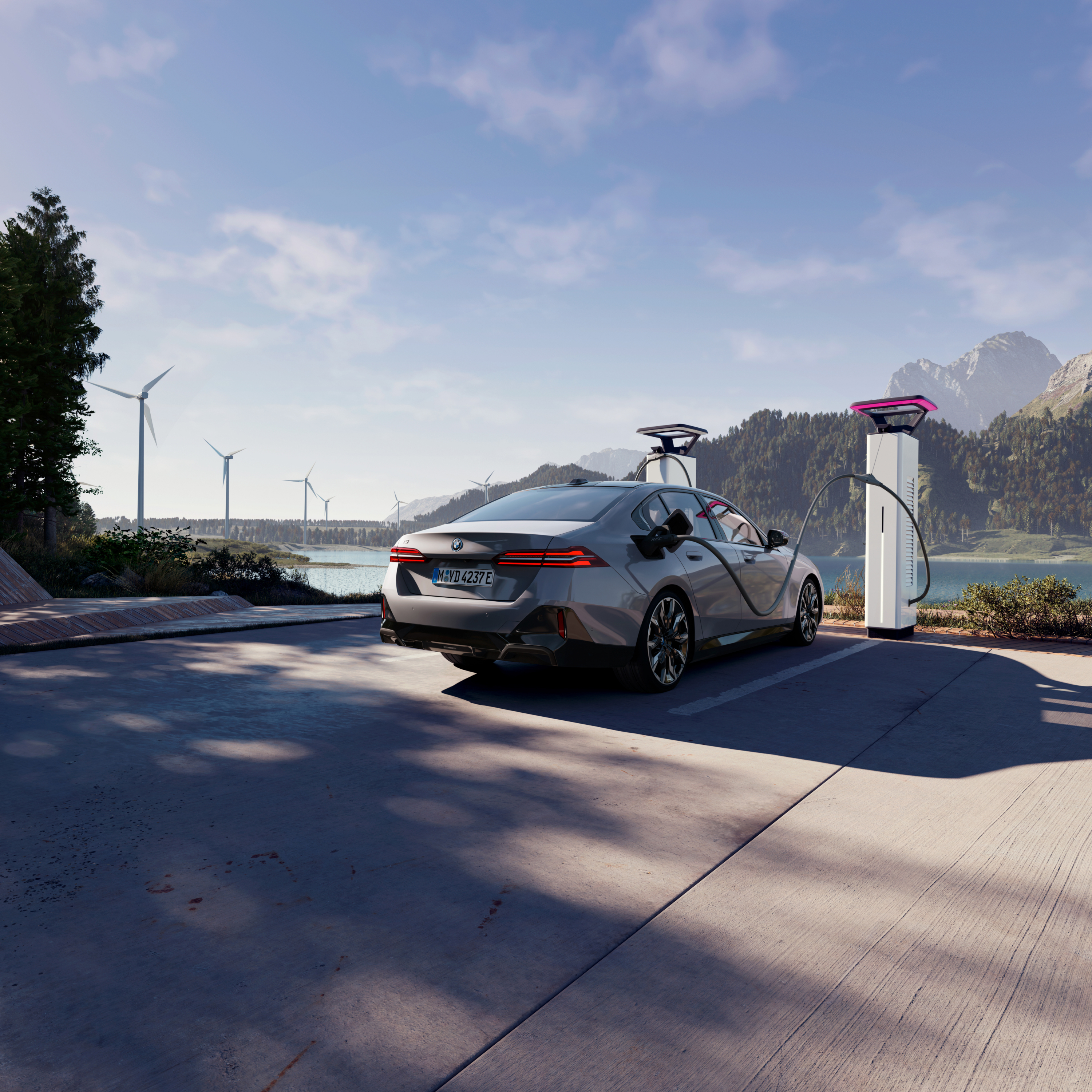 BMW lädt an Ladesäule mit Ausblick auf Wasser, Berge und Windräder