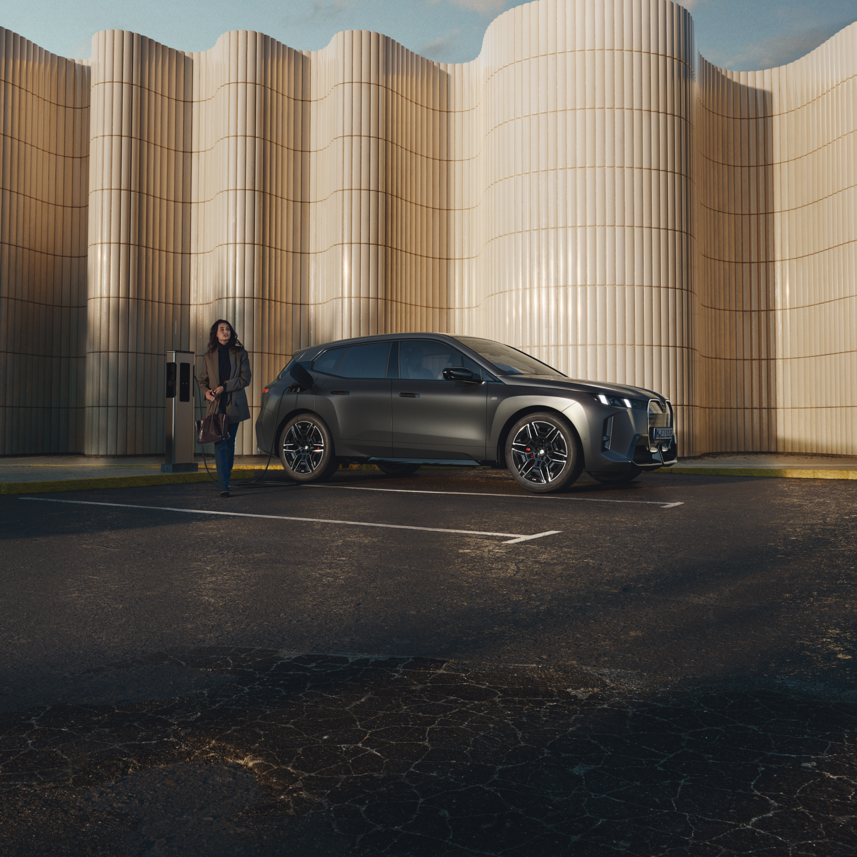 Person lehnt an BMW an öffentlicher Ladesäule am Straßenrand