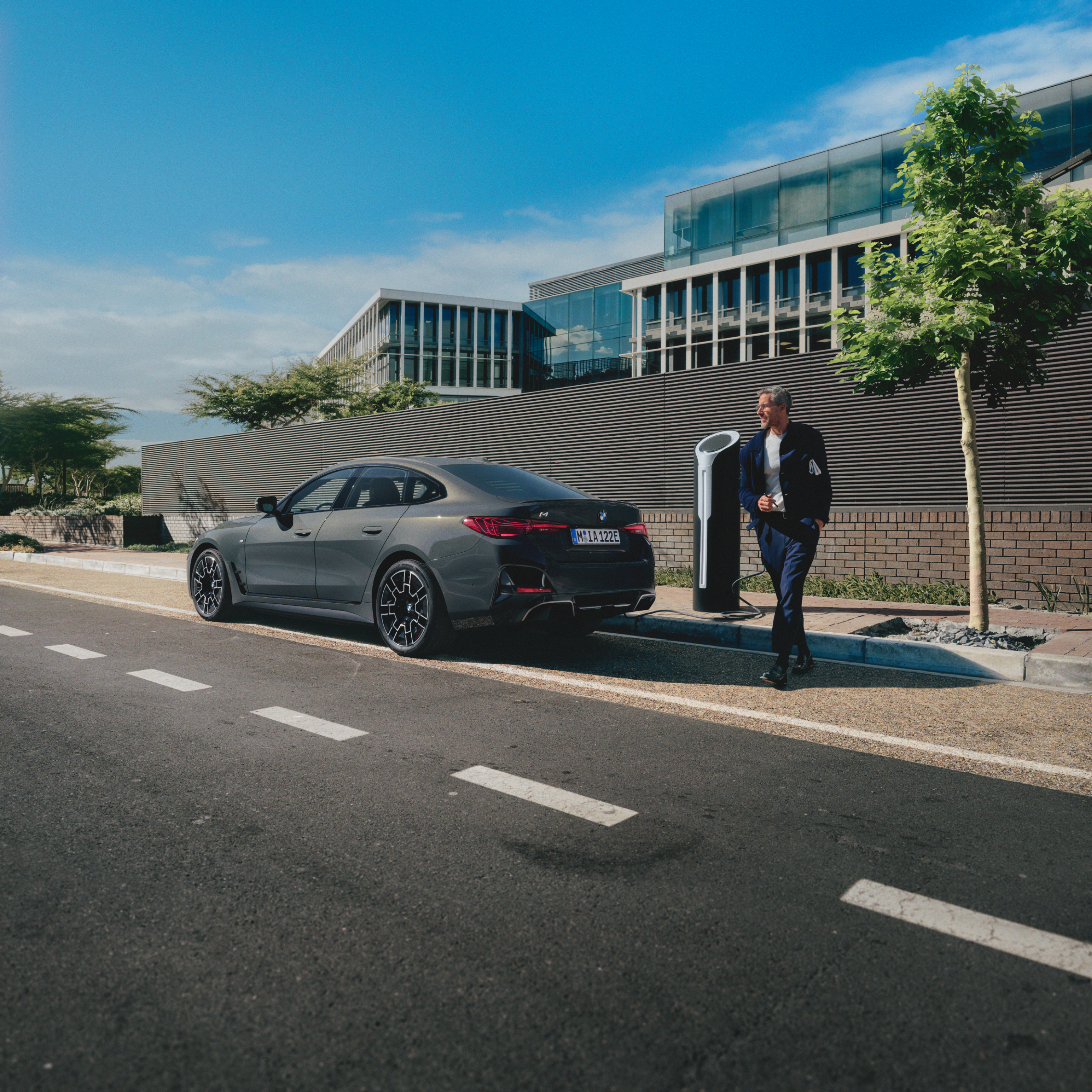 Person steht hinter ladendem BMW am Straßenrand