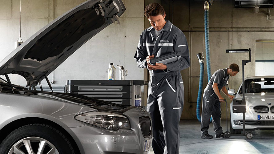 BMW Fahrzeug-Checks Mechaniker an offener Motorhaube in einer BMW Werkstatt