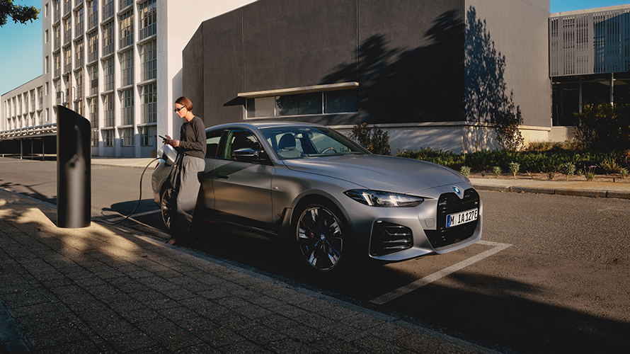 Eine Frau lehnt sich gegen einen ladenden BMW. Eine Frau lehnt sich gegen einen ladenden BMW.