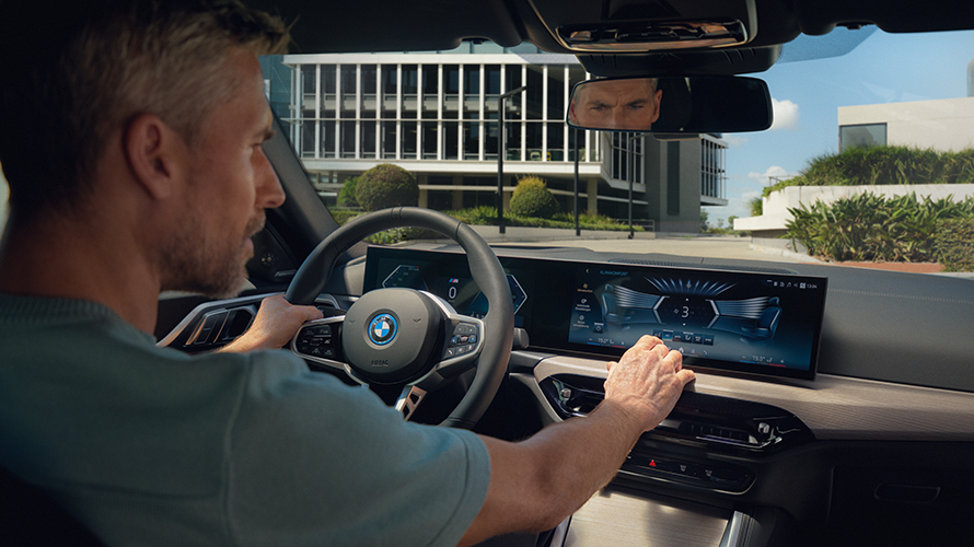 Ein Mann sitzt in einem BMW und bedient das Display. Ein Mann sitzt in einem BMW und bedient das Display.