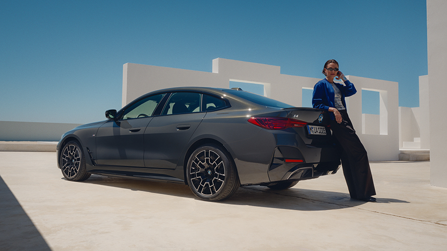 Eine Frau lehnt sich lässig gegen einen vollelektrischen BMW. Eine Frau lehnt sich lässig gegen einen vollelektrischen BMW.