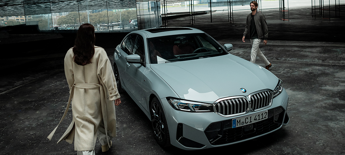Ein Mann und eine Frau gehen auf einen BMW zu.