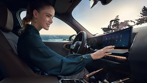 Eine Frau sitzt in einem BMW und bedient das Display. Eine Frau sitzt in einem BMW und bedient das Display.